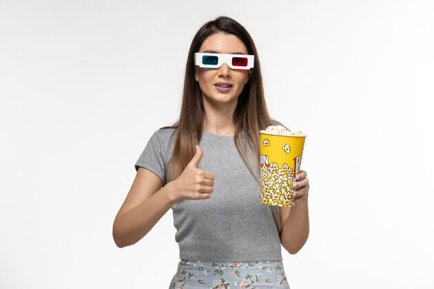太阳镜正面图年轻女性手持爆米花 戴着d型太阳镜在浅白色的表面上看电影漂亮前面电影院