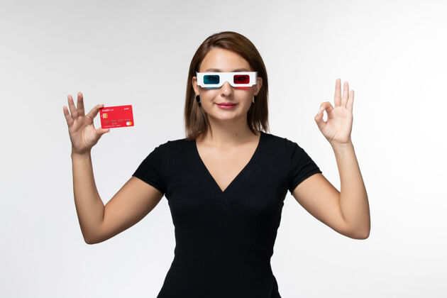年轻女性正面图年轻女性手持银行卡 戴着d型太阳镜 白色表面银行前面太阳镜