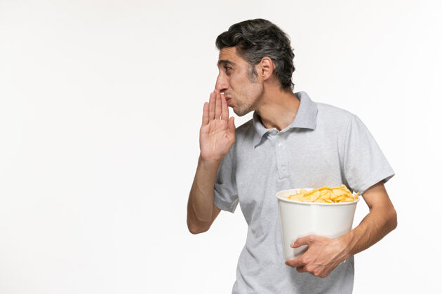 服务员正面图：年轻的男性拿着一个装着薯片的篮子 在一个白色的表面上与人交谈孤独年轻的男电影