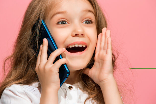 年轻快乐的少女站在时尚的粉色工作室墙上 用手机微笑着教育肖像情感