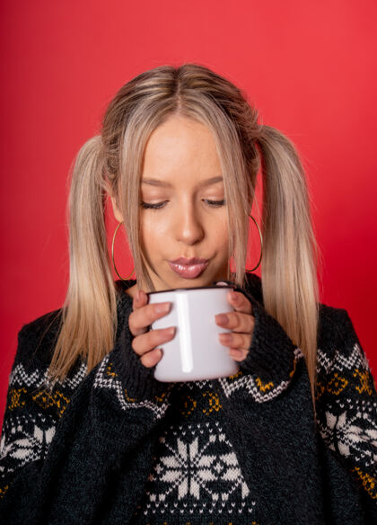 毛衣年轻的白人女性穿着可爱的毛衣 靠着红墙喝茶雪饮料棉花