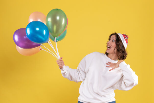 颜色正面图：手持黄色气球的年轻女子情感年轻女人正面