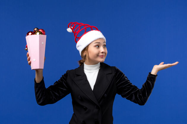 人前视图年轻女性手持蓝色背景的圣诞树玩具新年假期女人的颜色观点成功商人