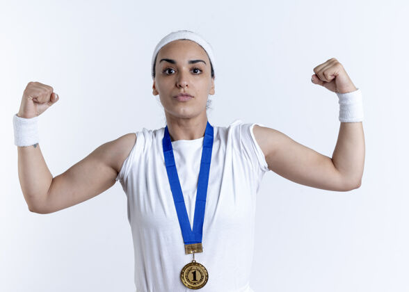 头带年轻自信的白人运动女性戴着头带和腕带与金牌紧张的二头肌隔离在白色空间与复制空间复制紧张腕带