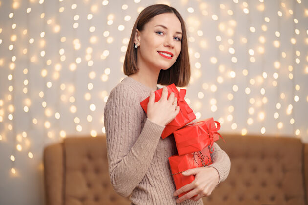 女士快乐的年轻女子拿着许多圣诞树和圣诞灯的礼物盒深色梦幻发光