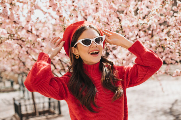 温柔的花戴着眼镜和红色贝雷帽的女人欣赏樱花的盛开穿着现金棉毛衣的女人微笑着外面是黑发女人的肖像女孩肖像天