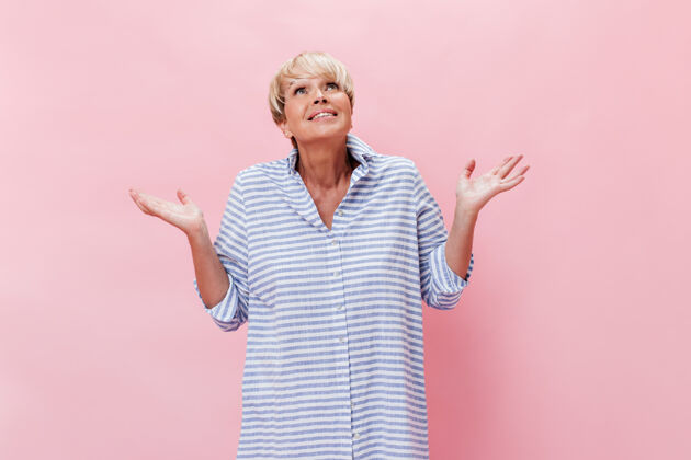 老年穿格子衬衫的女士在粉色背景上摆出一副误会的姿势微笑老年人成人