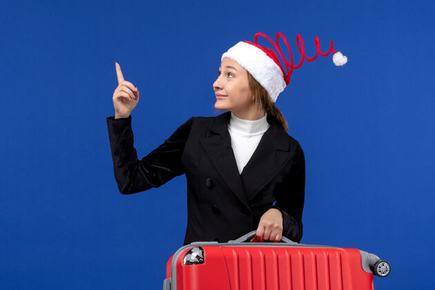 西装正面图：年轻女子背着红包在蓝色的墙壁上度假 女子度假工作圣诞节职业