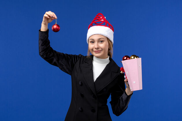 小姐前视图年轻女士拿着圣诞树玩具在蓝色的墙上蓝色的情感新年假期商人玩具人