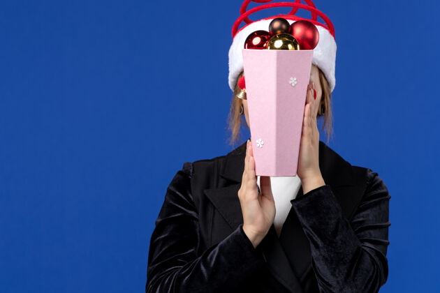 圣诞节正面图：年轻女性在蓝色墙壁上用玩具遮住她的脸新年假期尺子面具封面