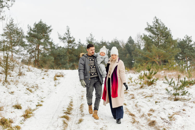 户外在一个阳光明媚的日子里 一家人在雪中散步 在冬季公园里玩得开心 互相拥抱 面带微笑玩耍雪快乐