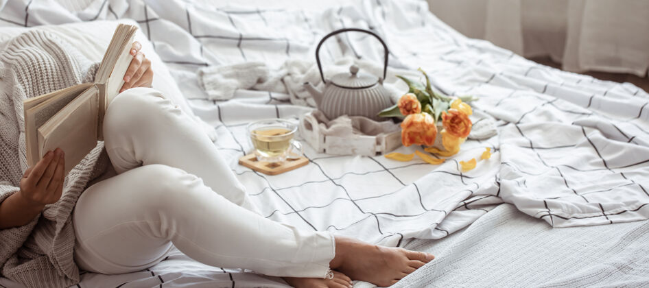 花束女人在床上看书 茶和郁金香的花束休息床房子