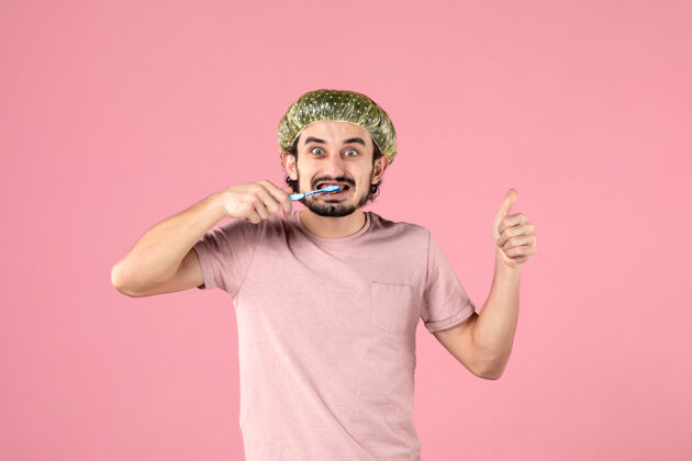 淋浴帽正面图：年轻男性在粉色背景上刷牙人牙齿年轻男性