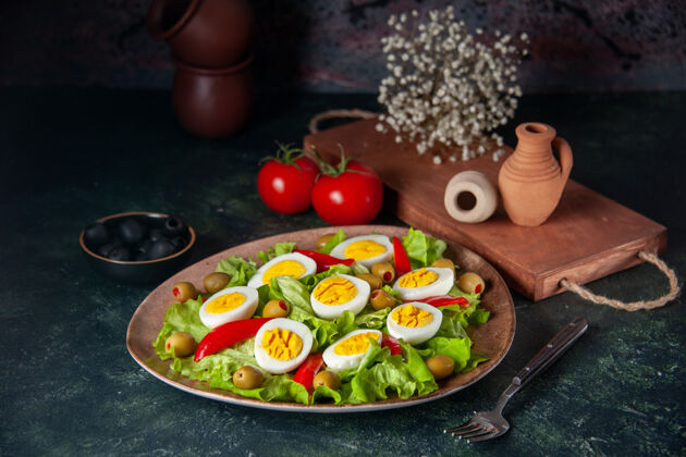 晚餐鸡蛋沙拉由橄榄和蔬菜沙拉组成 背景为深蓝色晚餐红辣椒盘子