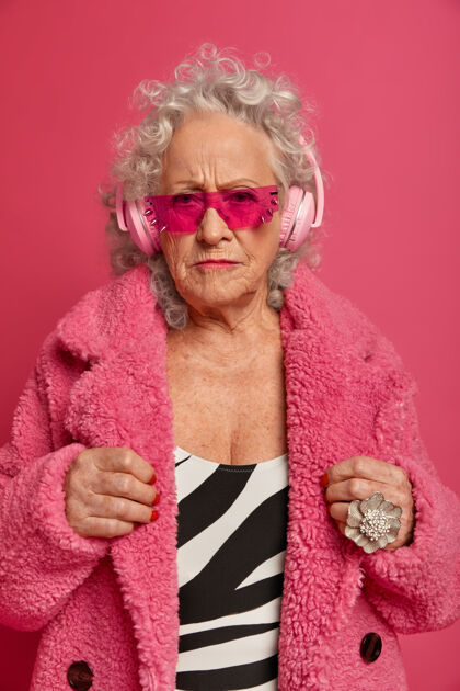 垂直穿着粉色紧身衣和外套 满脸皱纹的时尚老奶奶的特写照片成熟皱眉肖像