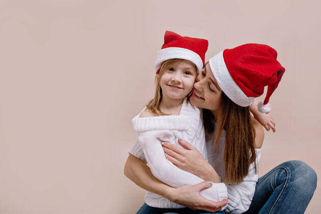 室内室内画室里 一位快乐的女人和她可爱的小女儿在隔离的米色墙上合影女人圣诞节圣诞树