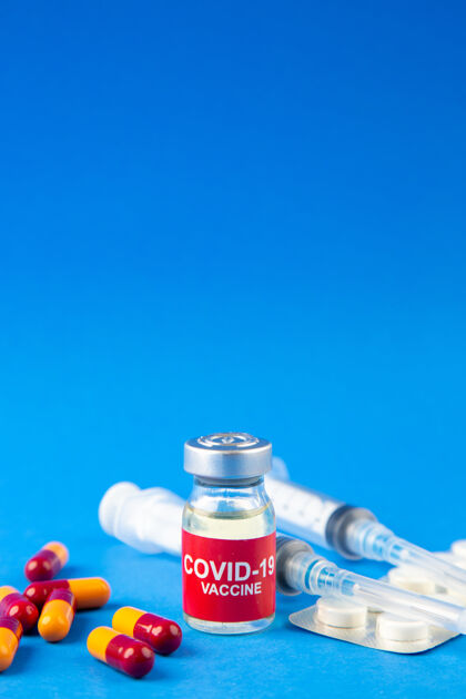 容器蓝色波浪背景上covid-19疫苗安瓿和胶囊包装药丸注射器的垂直视图包装玻璃治疗