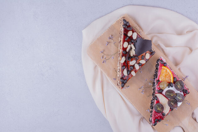 厨房三角形状的巧克力蛋糕片与坚果和水果放在一个木盘上糕点美味香草