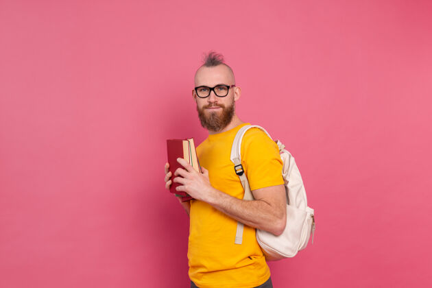学习一个留着胡子 背着书包 拿着书 穿着休闲装 快乐的成人学生文学眼镜英俊