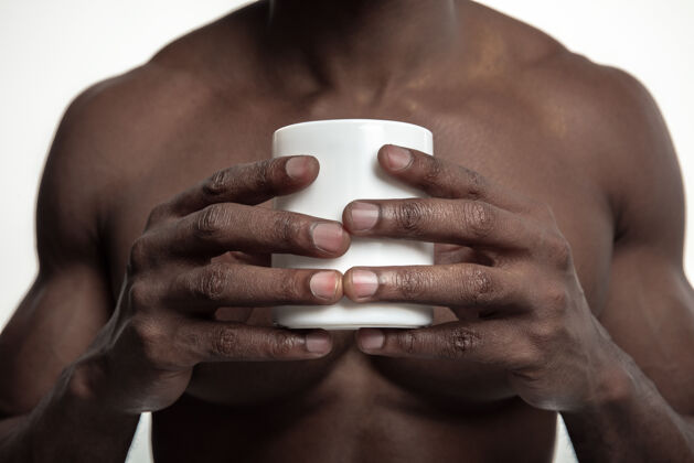 饮料一个非洲男人 喝着一杯白色的茶或咖啡 在白色的工作室里与世隔绝非洲咖啡美女