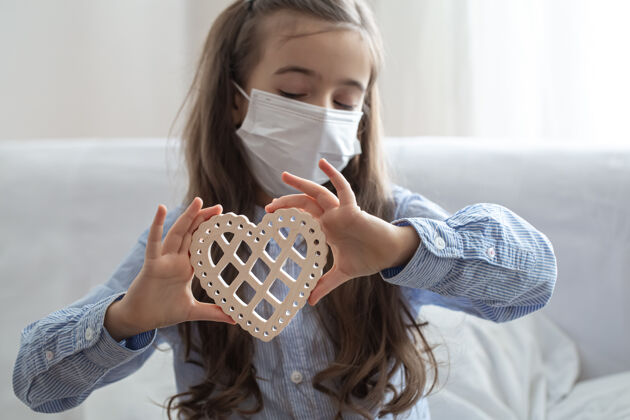 隔离孩子戴着医用防护口罩来保护身体免受冠状病毒侵害 抱着木心流行病女学生孩子