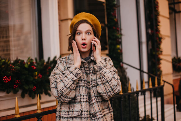 包一个女人在电话里用震惊的表情说话的特写照片美丽户外街道