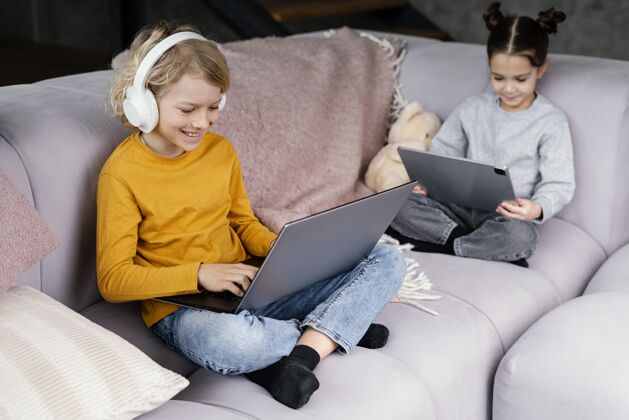 笔记本电脑兄弟姐妹坐在沙发上拿着笔记本电脑孩子小玩意兄弟姐妹