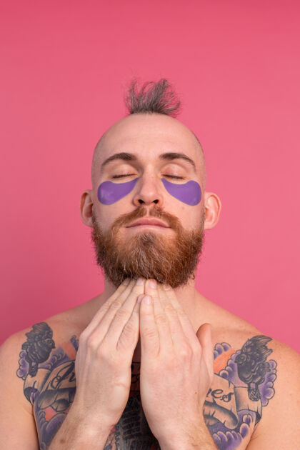 面膜欧洲帅哥留着胡子纹身上身的男人戴着紫色眼罩对着镜头摆粉红色的姿势阳性房子空虚