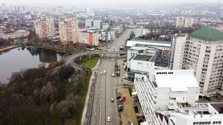 视图无人机俯瞰基希讷乌 街道上有多个住宅和商业建筑 道路上有移动的汽车 湖上有光秃秃的树木塔道路街道