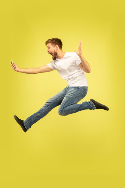 情绪黄色上孤立的快乐跳跃人的全长肖像男性消极休闲