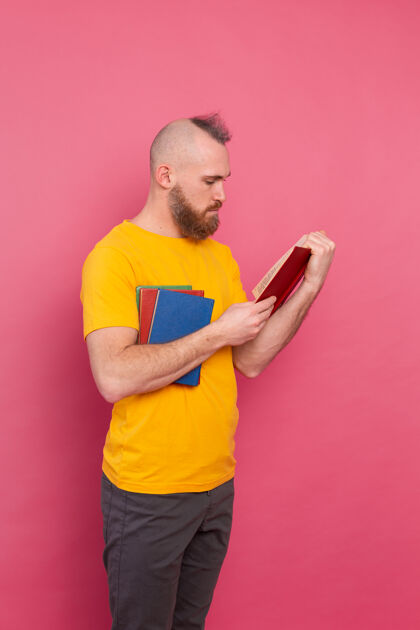 英俊留着胡子的欧洲男人 手里拿着一叠粉红色的书保持文学成功