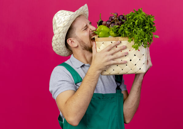 斯拉夫人年轻英俊的斯拉夫园丁 穿着制服 戴着帽子 手里拿着一篮子蔬菜 咬着制服男人帅哥