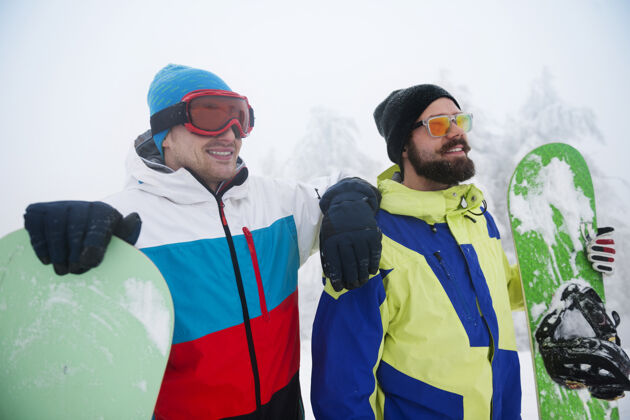 人两个家伙在寒假玩滑雪板运动享受帽子