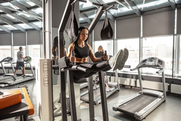 能量健康年轻肌肉发达的白人妇女在健身房练习器械运动女模特做腹肌锻炼 训练她的上身 腹部健康 健康的生活方式 健美杠铃健身室内