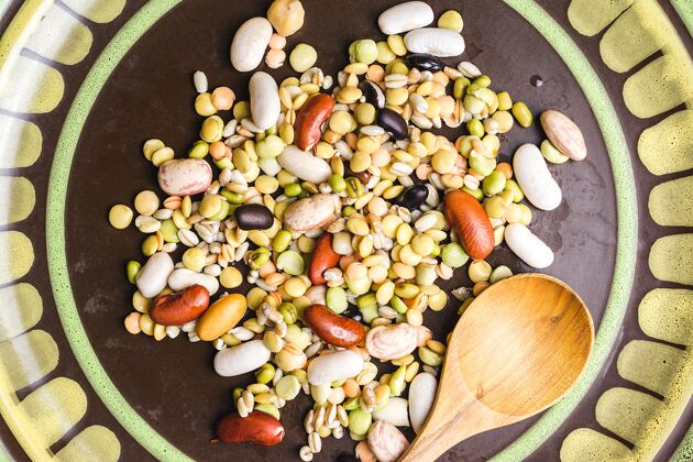 美食特写镜头混合豆在一个盘子里用木勺生的种子配料