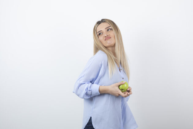 食物漂亮迷人的女模特站着 手里拿着一个新鲜的绿色苹果成熟拿着人