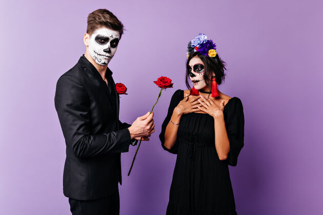 西班牙勇敢的年轻人给心爱的女孩一个惊喜 送给她一朵玫瑰墨西哥夫妇的头骨造型的面部艺术照恐怖死亡化妆舞会