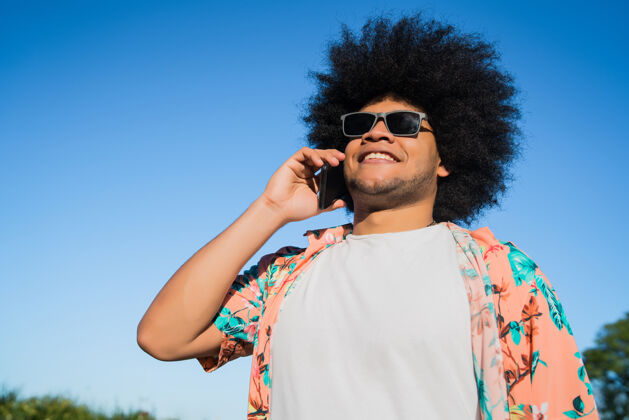 男性非裔拉丁男子站在街上打电话的画像看现代科技