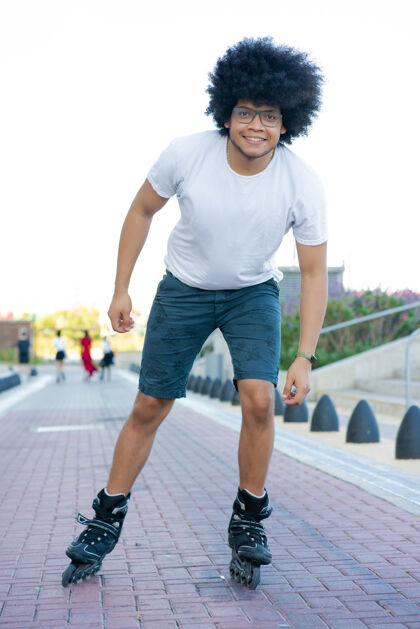 年轻人年轻的拉丁男子rollerskating在街上户外的肖像运动员乐趣活跃