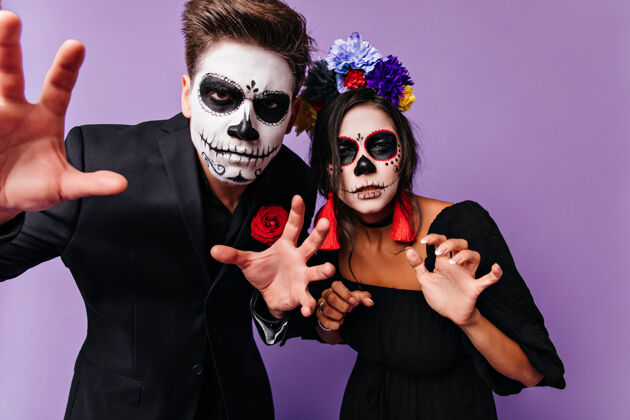 女人深色头发的年轻人在万圣节拍照时做鬼脸优雅的朋友们穿着僵尸服装在派对上玩得很开心墨西哥西班牙骷髅