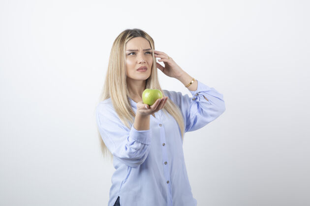 拿着漂亮迷人的女模特站着 手里拿着一个新鲜的绿色苹果水果苹果美味