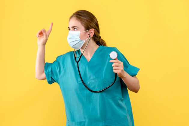 护士正面图黄色背景上戴口罩的女医生健康病毒大流行人冠状病毒比赛