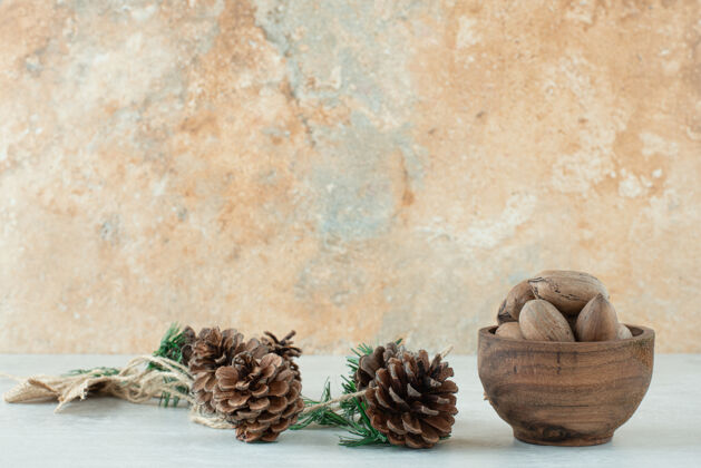 坚果白色背景上有松果的小木碗高质量的照片健康组小吃