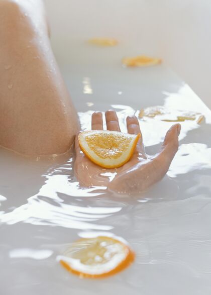 浴缸在水中用橘子片洗澡的女人橙色女性室内