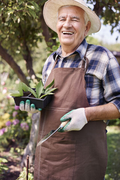 叶拿着花在地里干活的老人老年人防护手套护理