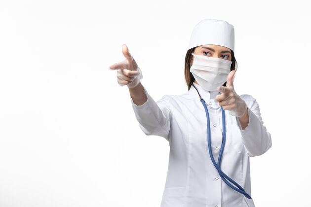 听诊器正面图女医生穿着白色医疗服 戴着口罩 因冠状病毒在淡白色墙壁上传播疾病大流行病毒女性大流行医院