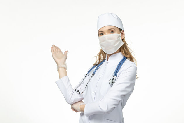 正面正面图女医生穿着医疗服 戴着口罩和手套 因冠状病毒在淡白墙上传播疾病大流行健康冠状病毒冠状病毒套装大流行