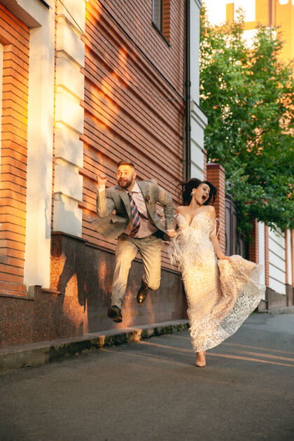 花高加索浪漫的年轻夫妇在城市里庆祝结婚温柔的新娘和新郎在现代城市的街道上家庭 关系 爱情的概念城市婚礼阳光