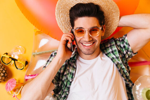 水果一个戴着橙色眼镜和草帽的年轻人的特写照片一个穿t恤的男人正躺在充气床垫上打电话背包正面太阳镜