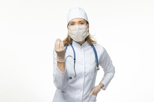 手套正面图女医生穿着医疗服戴着口罩和手套因冠状病毒在浅白墙上大流行冠状病毒病套装疾病视图